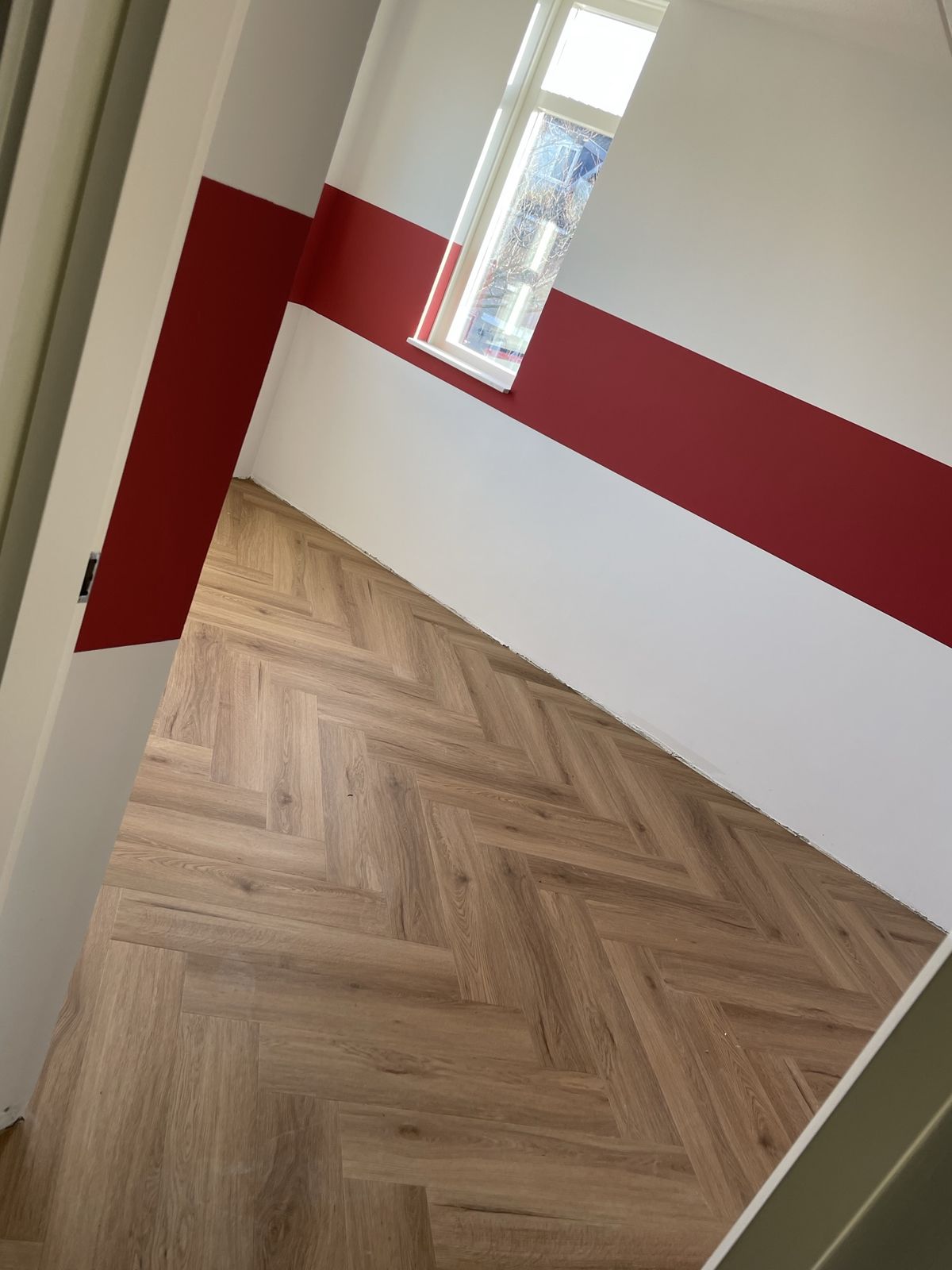 Kamer met witte wanden en een brede rode baan over de muur
